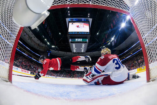 Michael Hage of Canada is being tripped by goaltender