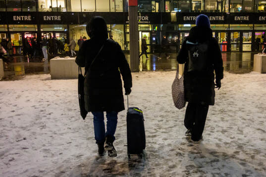 En person drar en rullväska i snön