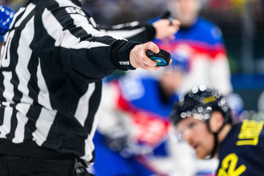 A game puck held by the referee in the men's ice hockey