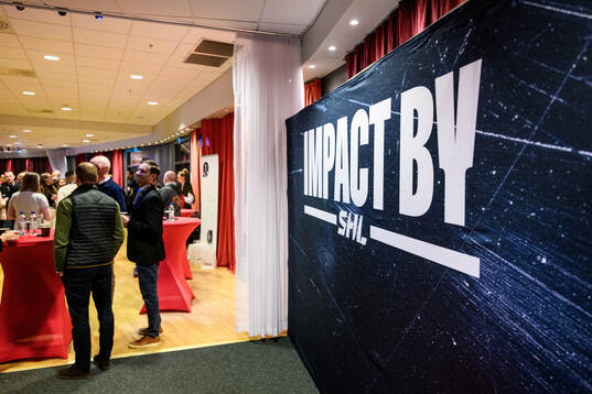 En skylt med Imapct By SHL