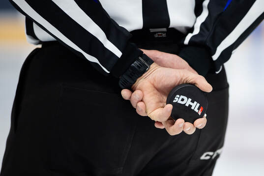 En domare med en puck i händerna