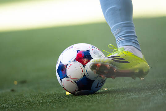 En fotboll och fotbollsko på konstgräs