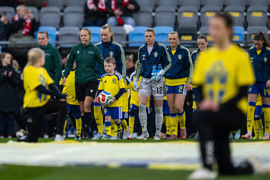 A mascot carrying the ball next to referee Ivana Martinčić