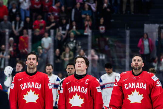 Dylan Demelo, Macklin Celebrini and Cam Talbot of Canada