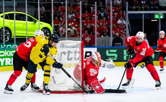 Rasmus Asplund of Sweden competes for the puck with Denis