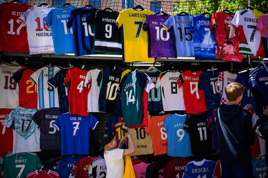 Kids inspect football jerseys for sale at a stand