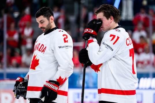 Dylan Demelo and Macklin Celebrini of Canada looks dejected