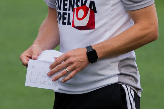 Assistant coach Sebastian Larsson with a paper at a