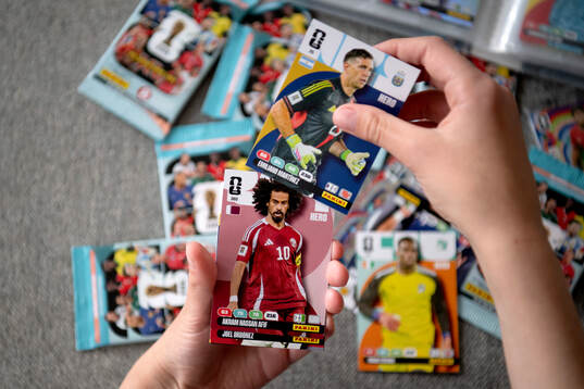 Två händer som håller i samlarbilder på fotbollsspelare