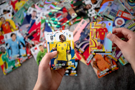 Två händer som håller i samlarbilder på fotbollsspelare