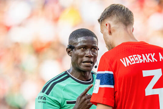 Referee Pierre Atcho talks to Kristoffer Ajer of Norway