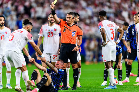 Referee Istvan Kovacs calls a yellow card and Yazan Alarab