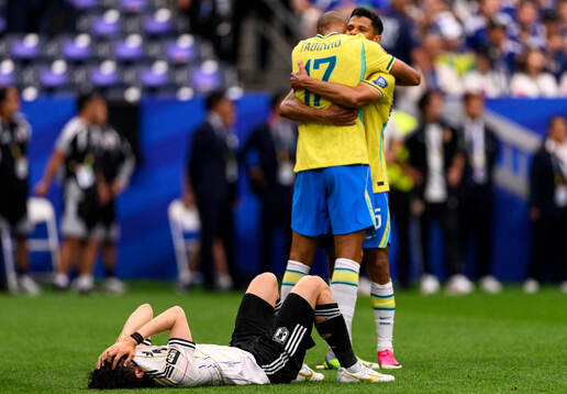 Fabinho of Brazil celebrates while a player of Japan looks
