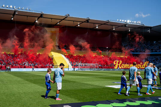 Malmö FFs spelare går in med supportrarnas tifo i
