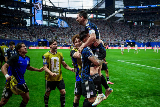 Enzo Fernandez hoists Lionel Messi of Argentina