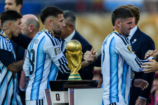 The trophy in front of Nicolas Otamendi and Rodrigo De Paul