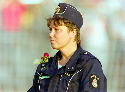 A swedish policewoman at the game with a flower she