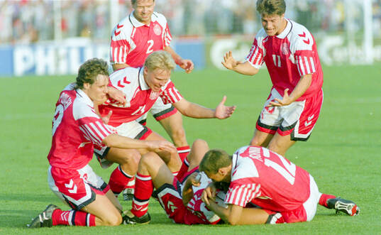 Denmarks John Jensen is mobbed by team mates