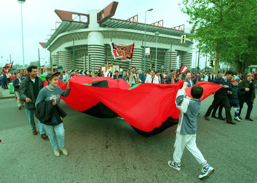Milan-supportrar med flagga utanför Giuseppe Meazza -
