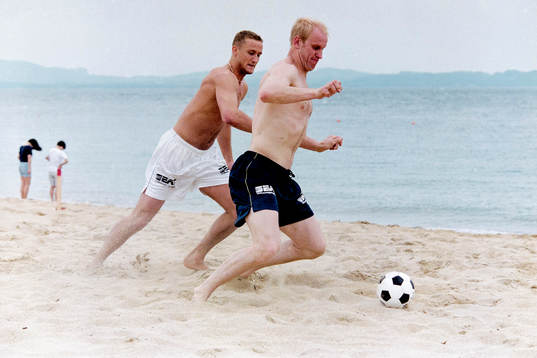 Andreas Larsson och Mats Olsson spelar fotboll på stranden